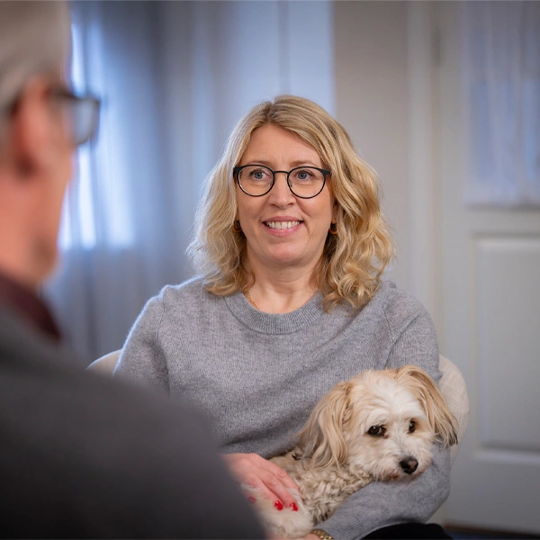 Bild på psykolog Lena Norell som håller en hund och samtalar med en klient